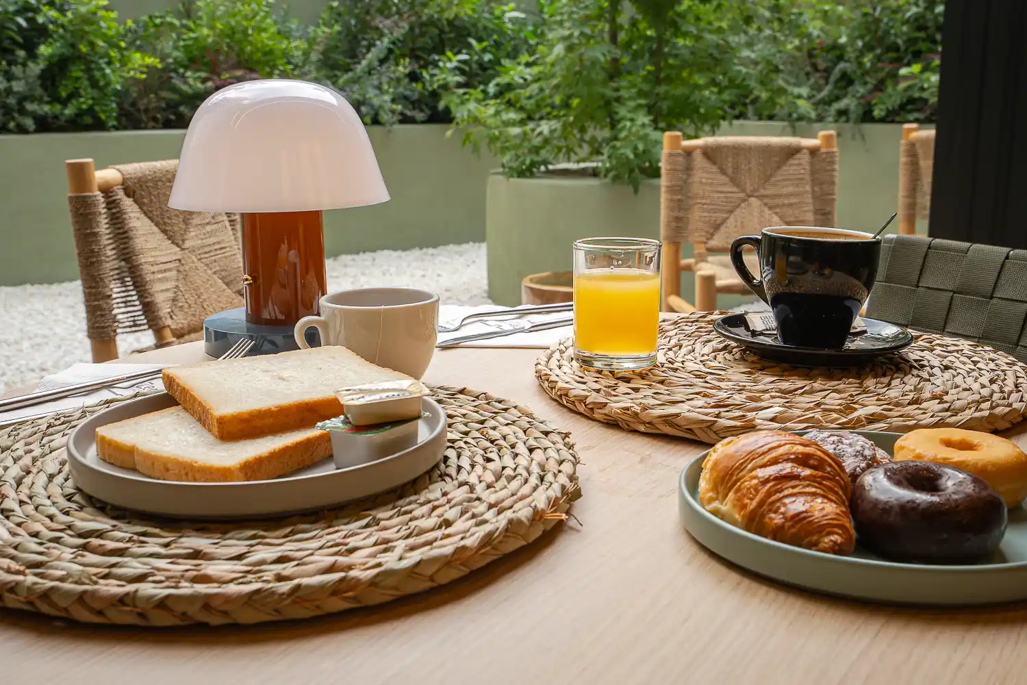 Desayuno en el patio con tostadas, croissant, donuts, café y zumo de naranja