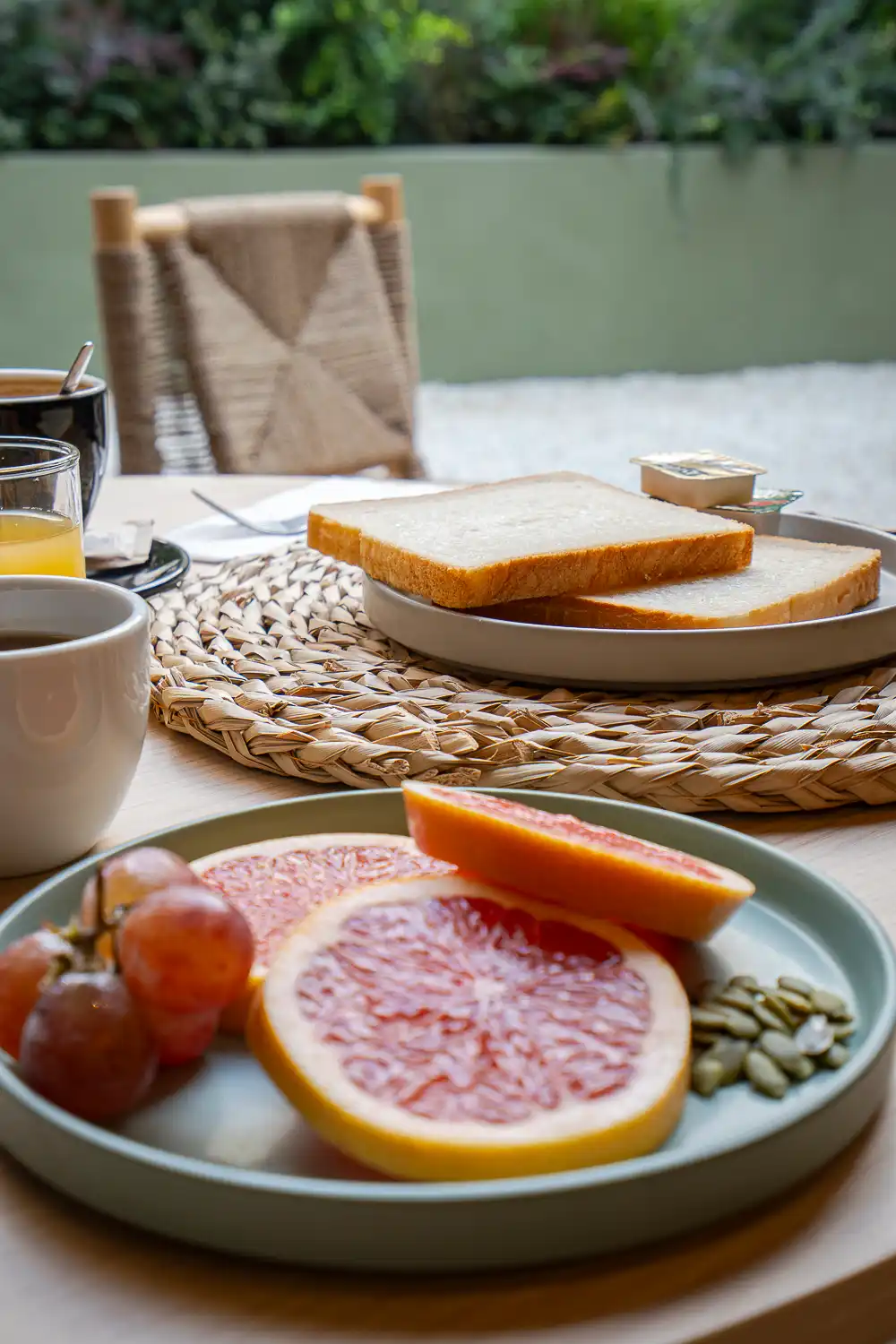 Pomelo, uvas, pipas de calabaza y tostadas en una mesa del patio