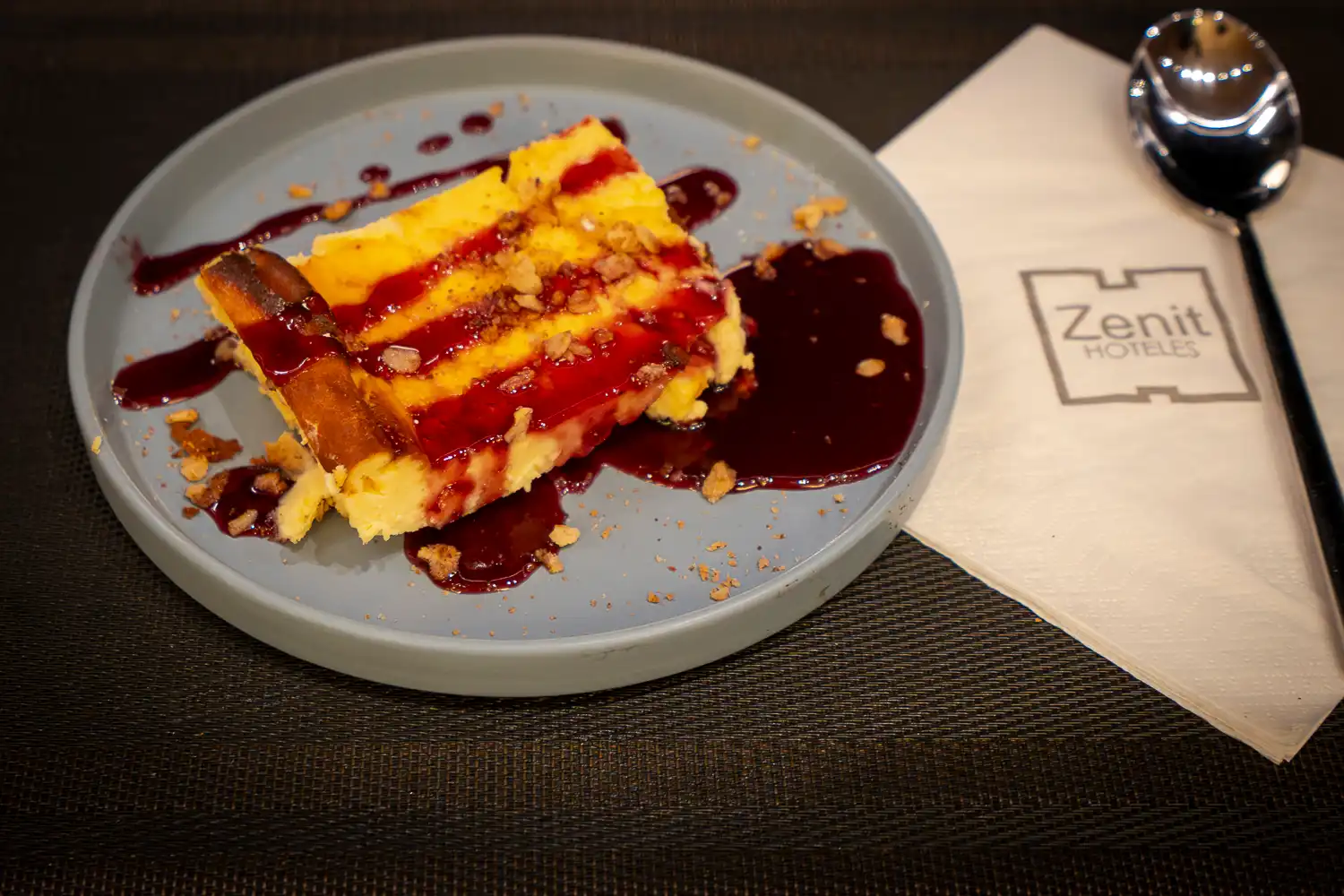 Porción de tarta de queso con coulis de frutos rojos por encima